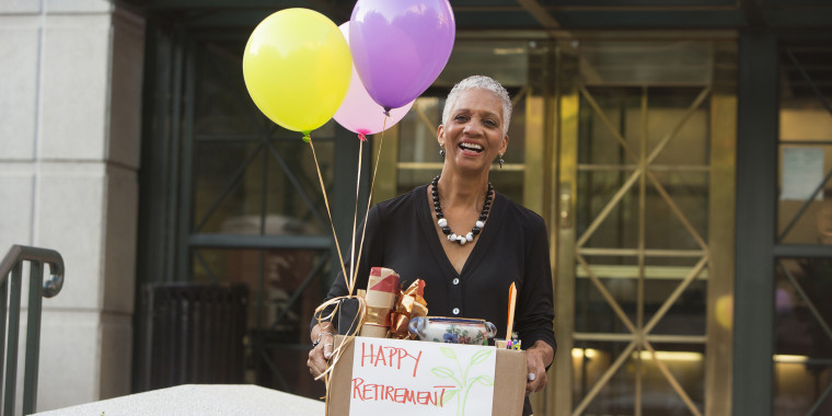 Black woman carrying belongings with happy retirement sign and balloons