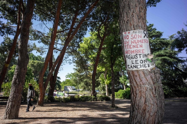 Image: A man walks past a sign on a tree reading "They are not just a number, they have a name. Agustina Leon Sanchez, 79, May 1, 2020" in memory of a victim of the COVID-19 disease in Madrid