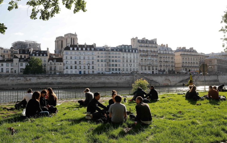 Image: People gather along banks of the Seine river in Paris, on Monday