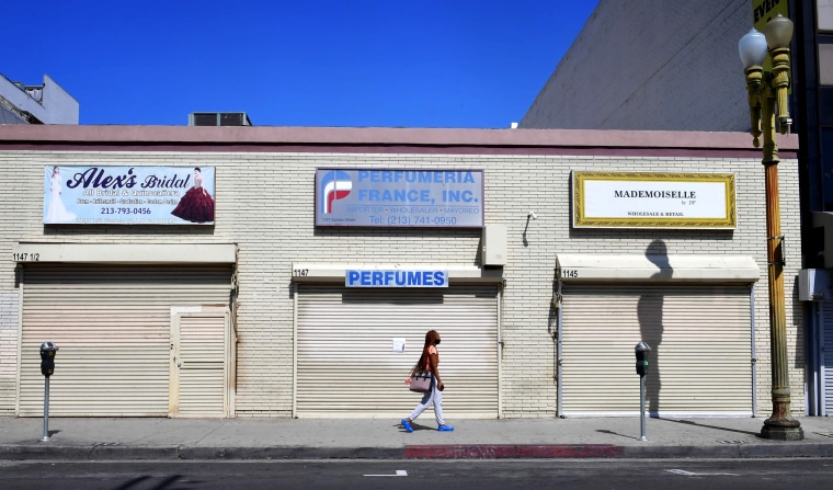 Image: A woman walks past closed storefronts in Los Angeles on May 4, 2020.
