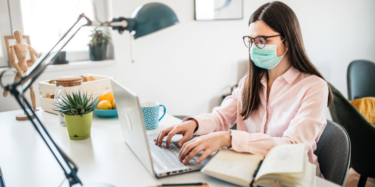 Portrait of a young woman working in her office and wearing face mask.