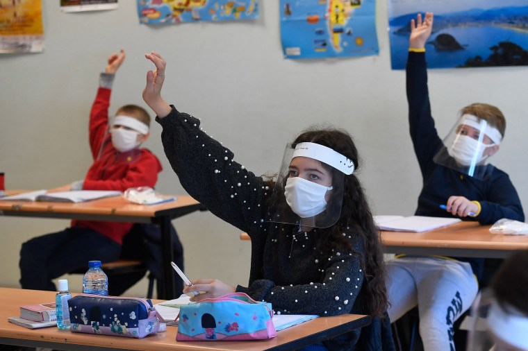 Image: Schoolchildren wearing protective mouth masks and face shields attend a course in a classroom at Claude Debussy college in Angers, western France, on May 18, 2020 after France eased lockdown measures to curb the spread of the COVID-19 pandemic