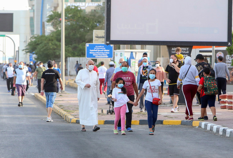 Image: Mask-clad residents walk in Kuwait City on May 12.