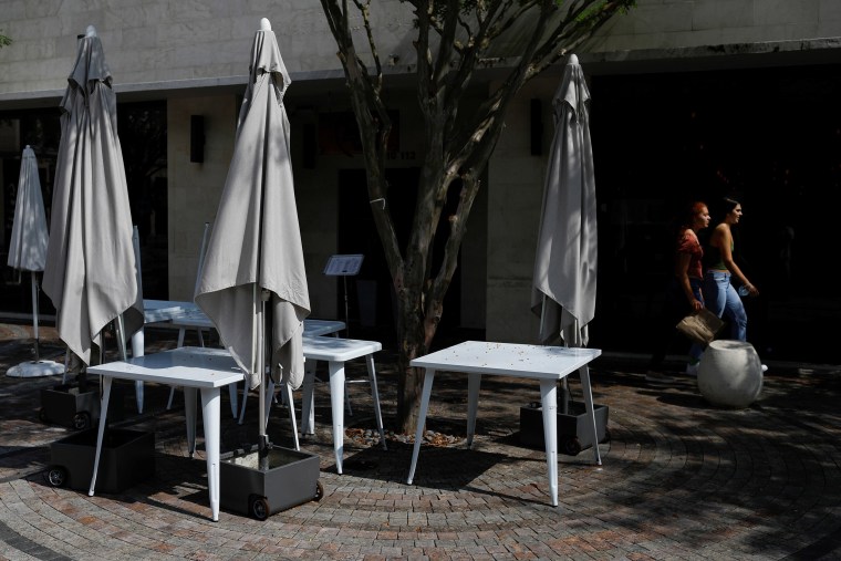 Image: Women walk past empty tables outside a restaurant, as Miami-Dade County eases some of the lockdown measures put in place during the coronavirus disease (COVID-19) outbreak, in Miami