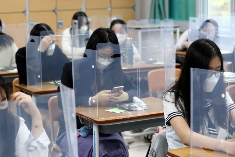 Image: High school students wearing face masks prepare for classes, with plastic covers placed on desks to prevent infection, as schools reopen following the global outbreak of the coronavirus disease (COVID-19), in Daejeon, South Korea