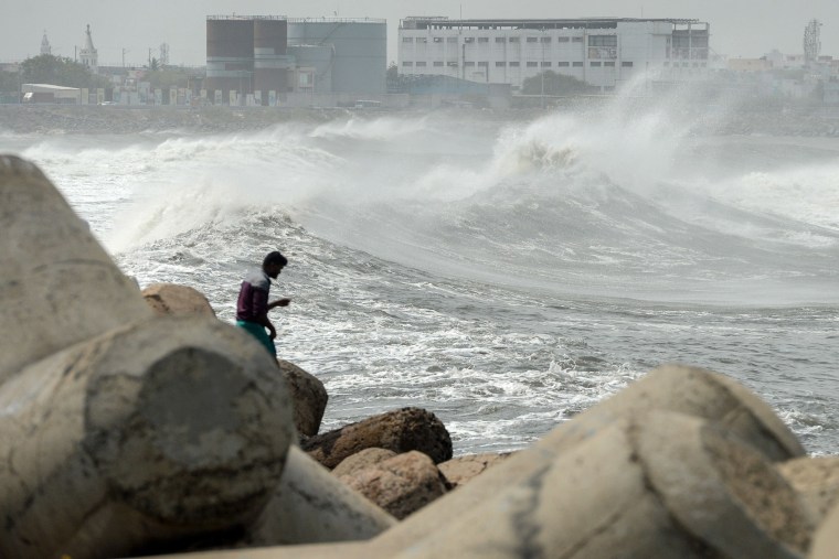 Image: A man looks out as waves hit a breakwater at Kasimedu fishing harbour in Chennai