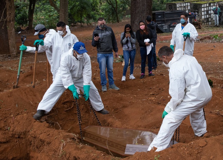 Image: Adenilson Souza Costa, 47 years, and his coworkers wearing protective gear bury a coffin during a burial at Vila Formosa Cemetery amidst the coronavirus (COVID-19) pandemic