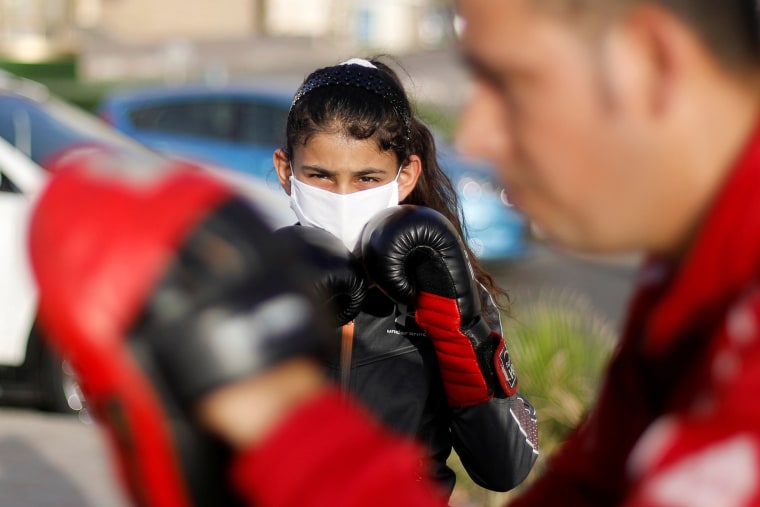Image: A Palestinian girl is instructed by coach Osama Ayob on Thursday during a boxing training session on the sidewalk of a beach as sports clubs are closed due to coronavirus fears in Gaza City.