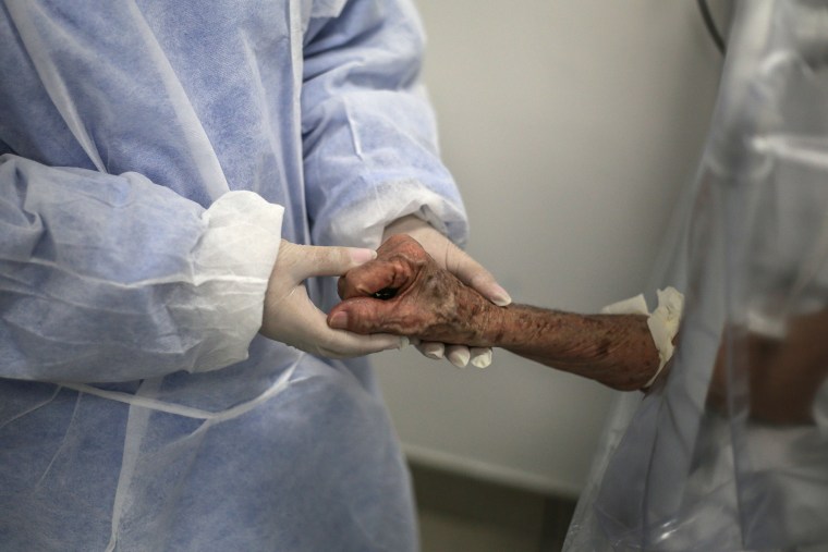 Image: A nurse holds the arm of a patient infected with COVID-19 at the Gilberto Novaes Municipal Field Hospital on Thursday in Manaus, Brazil.