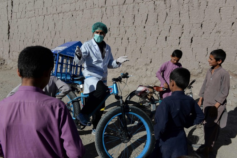 Image: 27-year-old Afghan cyclist Idrees Syawash talks to residents during his awareness campaign against the COVID-19 coronavirus in the Surkh Rod district of Nangarhar province