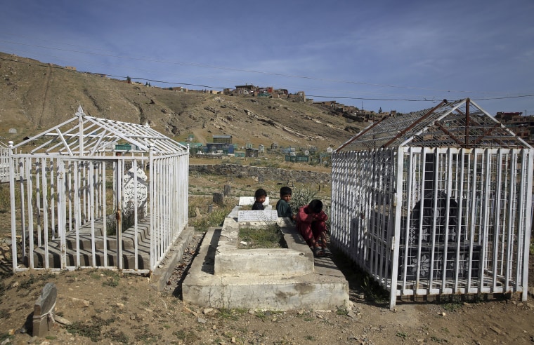 Image: Afghan children sit on a grave on the outskirts of Kabul, Afghanistan