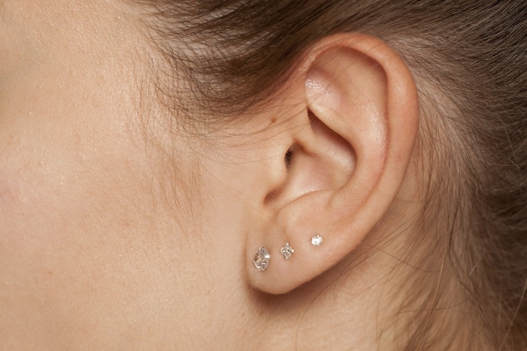 Closeup of female ear with three earrings