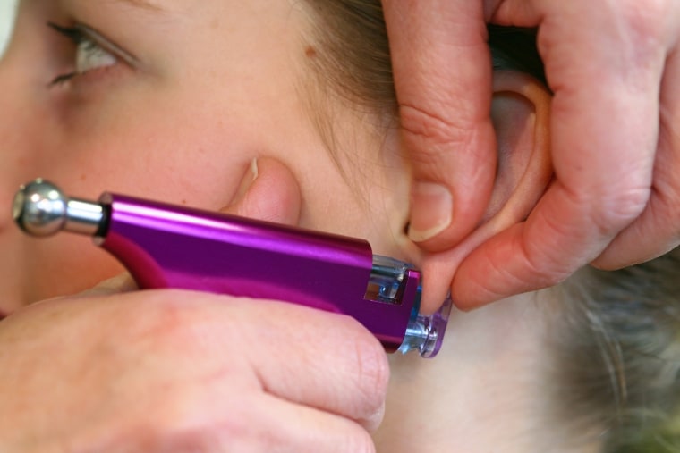 Young girl's headshot, having first earrings shot with purple pistol