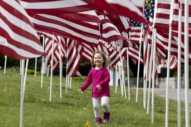 Image: Hazel Roberts walks through a field of flags ahead of Memorial Day in Cohasset, Mass., on May 23, 2020.