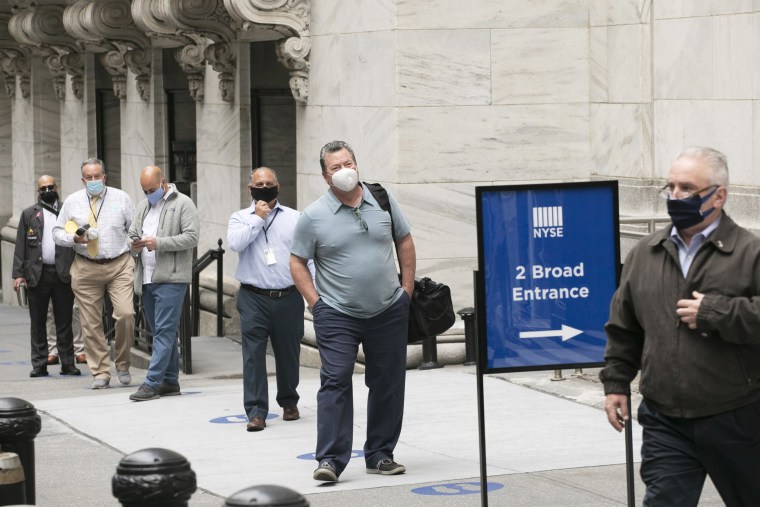 New York Stock Exchange employees wait to enter the building as the trading floor partially reopens on May 26, 2020.