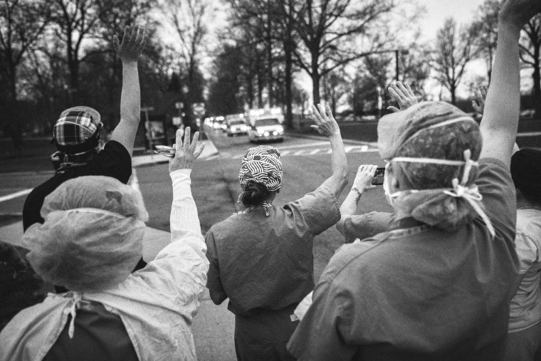 Image: Health care workers from Westchester Medical Center wave and cheer as first responders pass by in a caravan of lights and sirens in Valhalla, N.Y., on April 14, 2020.