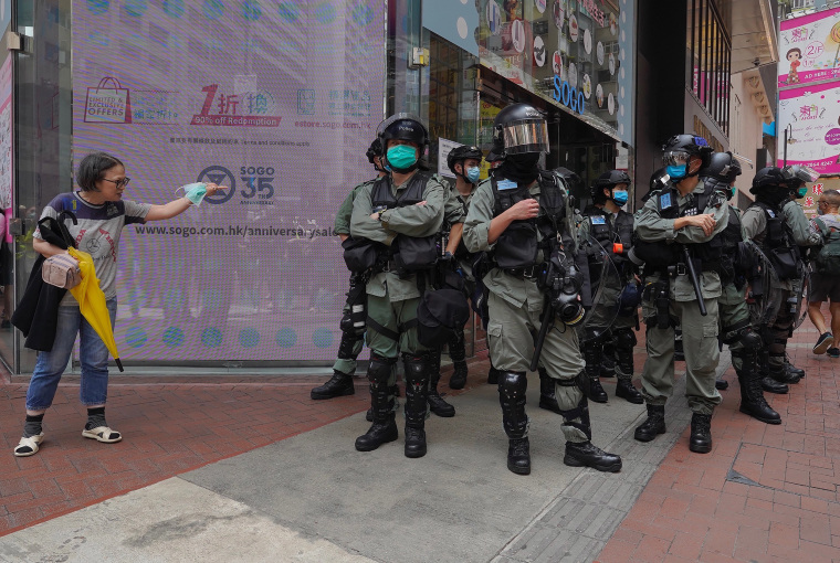 Image: Riot police standing guard as a woman tries to cross the street in the Central district of Hong Kong