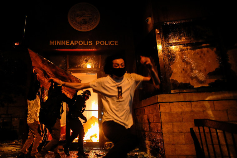 Image: Protesters react as they set fire to the entrance of a police station as demonstrations continue in Minneapolis
