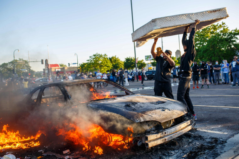 Protesters throw a mattress onto a burning car outside a Target store near the 3rd Precinct on May 28, 2020 in Minneapolis.