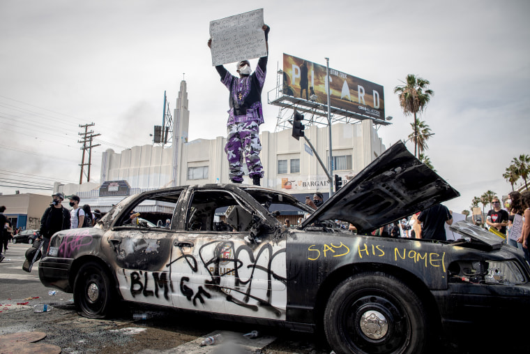 Image: A protester stands on top of a damaged police car in the Fairfax district of Los Angeles on May 30, 2020.