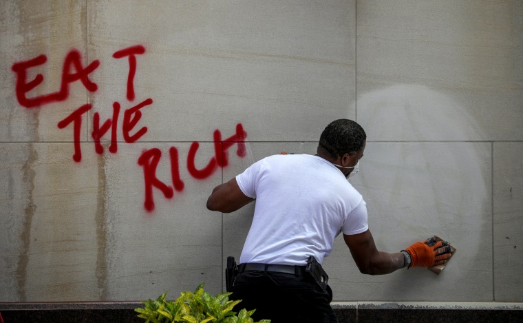 Image: A man cleans a wall of graffiti after a night of demonstrations in Washington, D.C., on May 31, 2020.