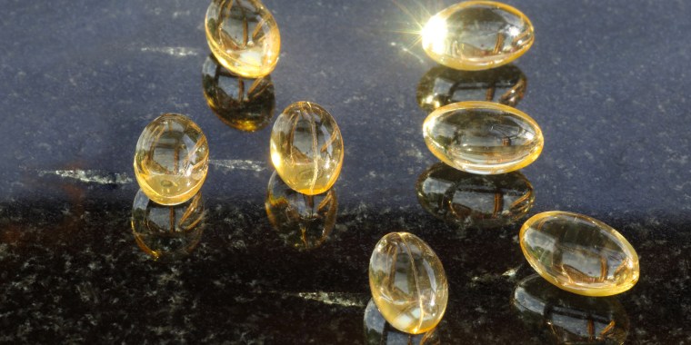 Vitamin D3 capsules glisten on shiny black surface