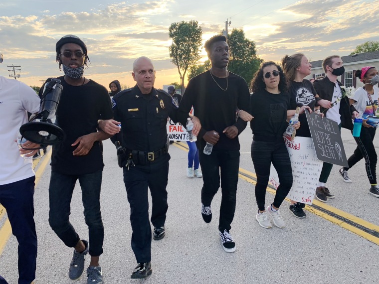 Image: Police officers in Fallon, Missouri walk arm in arm with demonstrators