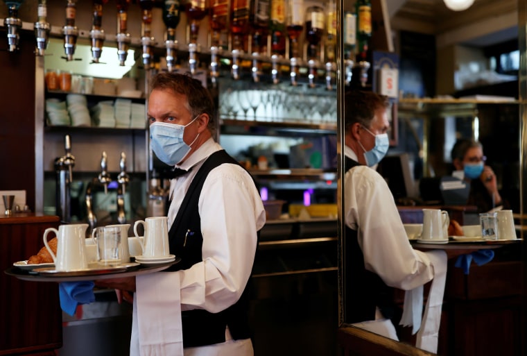 Image: A waiter wearing a face mask serves at Cafe de Flore, as restaurants and cafes reopen following the coronavirus disease (COVID-19) outbreak, in Paris, France