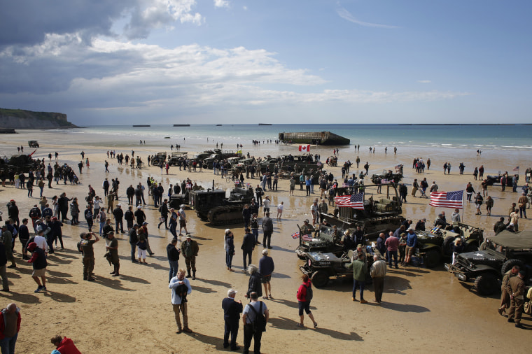 Image: People walk among vintage World War II vehicles parked on the beach during events to mark the 75th anniversary of D-Day in Arromanches, Normandy, France