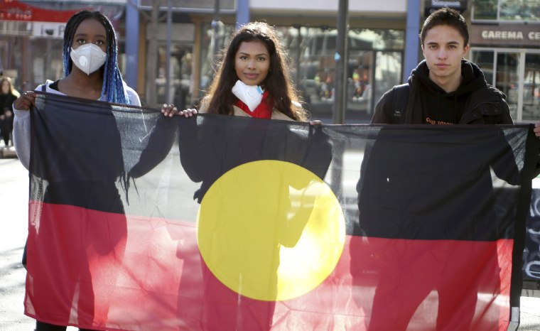 Image: Protesters hold an Aboriginal flag in Canberra, Australia on Friday.