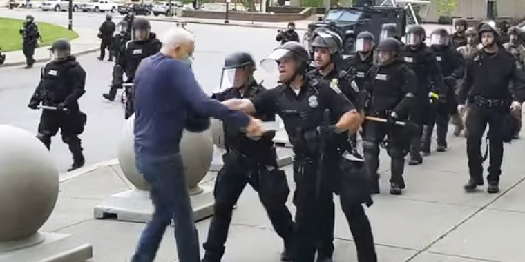 In this image from video provided by WBFO, a Buffalo police officer appears to shove a man who walked up to police Thursday, June 4, 2020, in Buffalo, N.Y. Video from WBFO shows the man appearing to hit his head on the pavement, with blood leaking out as officers walk past to clear Niagara Square. Buffalo police initially said in a statement that a person "was injured when he tripped & fell," WIVB-TV reported, but Capt. Jeff Rinaldo later told the TV station that an internal affairs investigation was opened. Police Commissioner Byron Lockwood suspended two officers late Thursday, the mayor's statement said. (Mike Desmond/WBFO via AP)