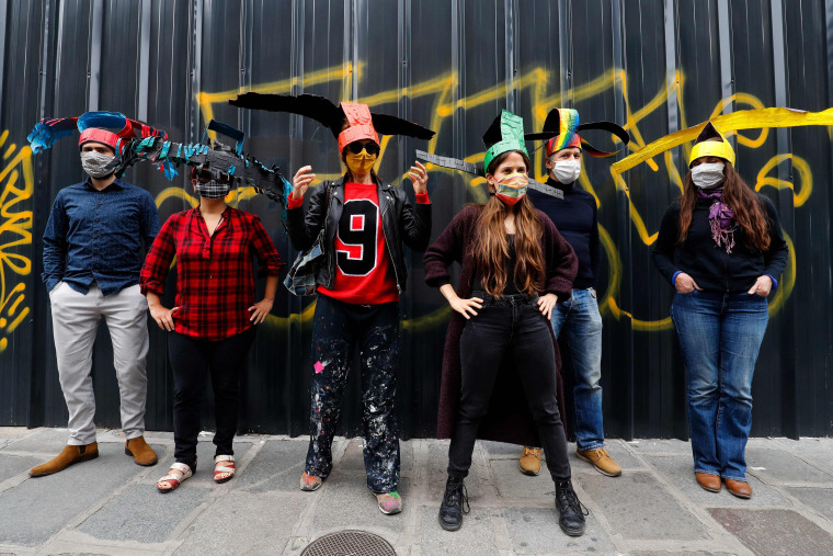 Image: Artists and residents of the artist squat "59 Rue de Rivoli" pose in Paris, on June 9, 2020 with  hats made by French artist Dominique Pouzol and created to keep the social distance required to fight against the spread of the COVID-19