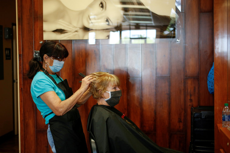 Image: Donna Ferraro cuts and styles Jan Campbell?s hair at Passions Salon during the phased reopening from the coronavirus disease (COVID-19) restrictions, in Cave Creek