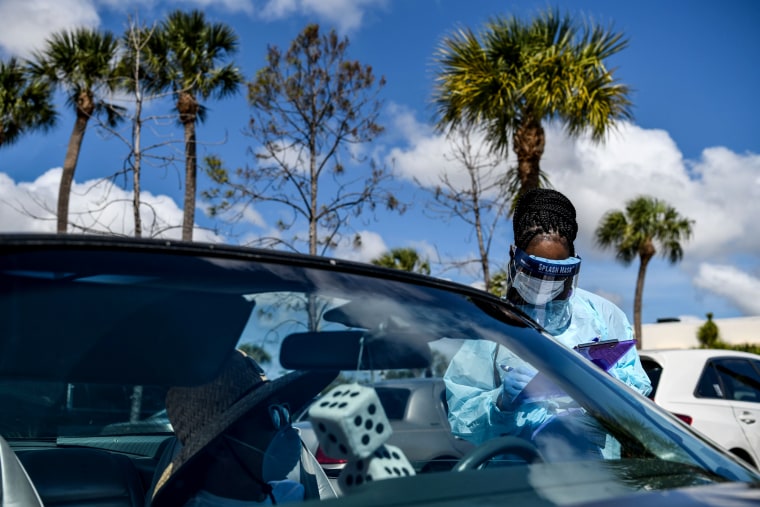 Image: A medical worker fills out a form while speaking to a driver at a drive-thru coronavirus testing lab in West Palm Beach, Fla., on March 16, 2020.