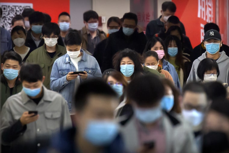 Image: Commuters wear face masks to protect against the spread of new coronavirus as they walk through a subway station in Beijing,