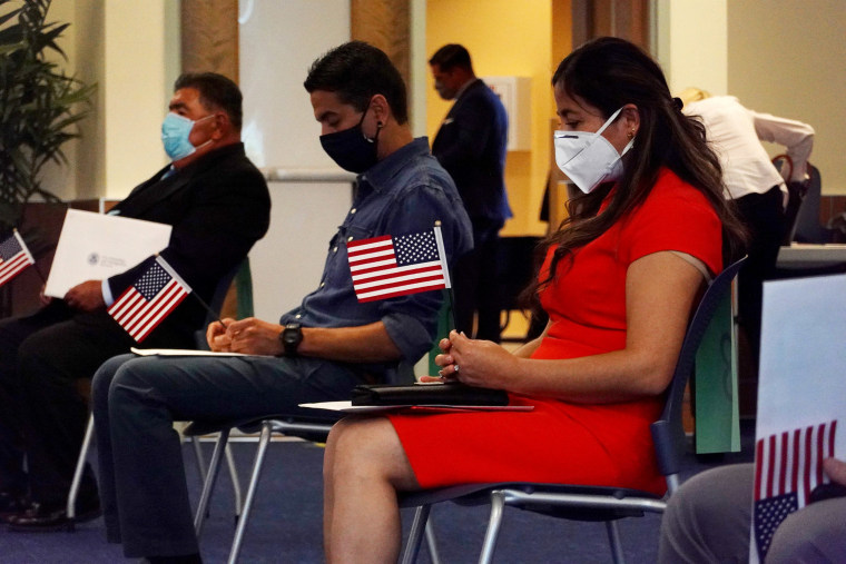 Image: Giagnna Mendez, originally from Peru, wearing a mask to protect against the coronavirus participates in a swearing in ceremony to become an American citizen held at the U.S. Citizenship and Immigration Service's Kendall office