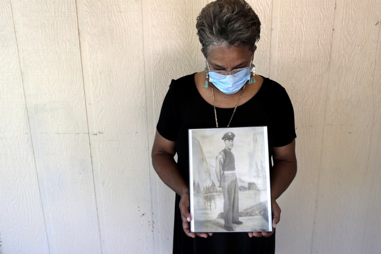 Belvin Jefferson White poses with a portrait of her father Saymon Jefferson at Saymon's home in Baton Rouge, La. on May 18, 2020. Belvin recently lost both her father and her uncle, Willie Lee Jefferson, to COVID-19.