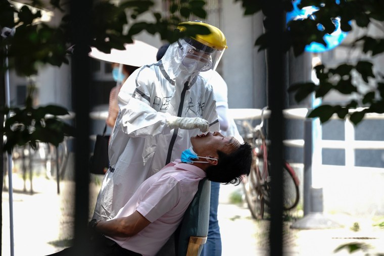 Image: A nurse wearing a protective suit and mask takes a nucleic acid test for COVID-19 from a person who either visited or lives near the Xinfadi Market at a testing facility at a Sport Center on June 16, 2020 in Beijing, China.