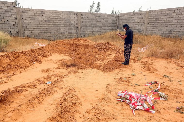 Image: A member of security forces affiliated with the Libyan Government of National Accord (GNA)'s Interior Ministry stands at the reported site of a mass grave in the town of Tarhouna