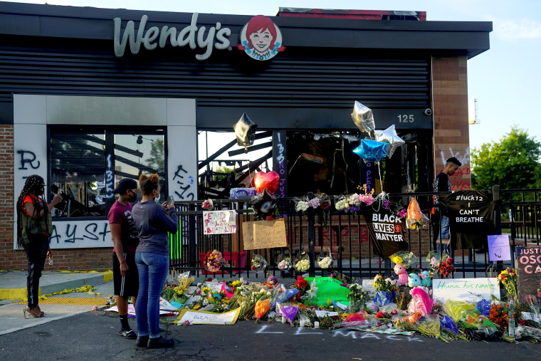 Image: People take photos of a memorial to Rayshard Brooks at the Wendy's where he was shot and killed by police officers, in Atlanta