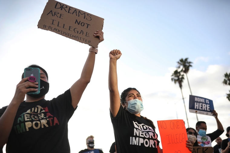 Image: People hold signs and a woman raises her fist during a rally in support of the Supreme Court's ruling in favor of the Deferred Action for Childhood Arrivals (DACA) program, in San Diego, California