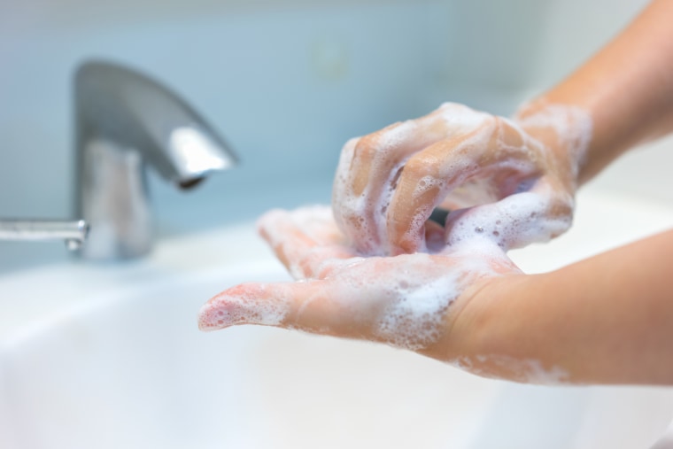 Cropped Image Of Woman Washing Hands In Bathroom Sink