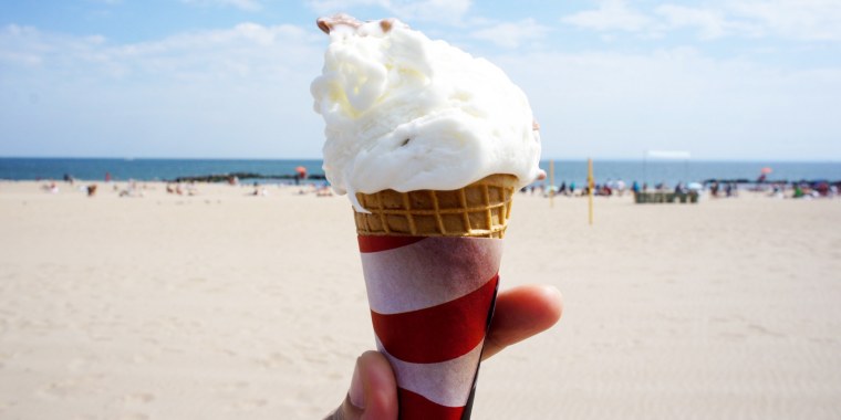 Close-Up Of Hand Holding Ice Cream Cone At Beach