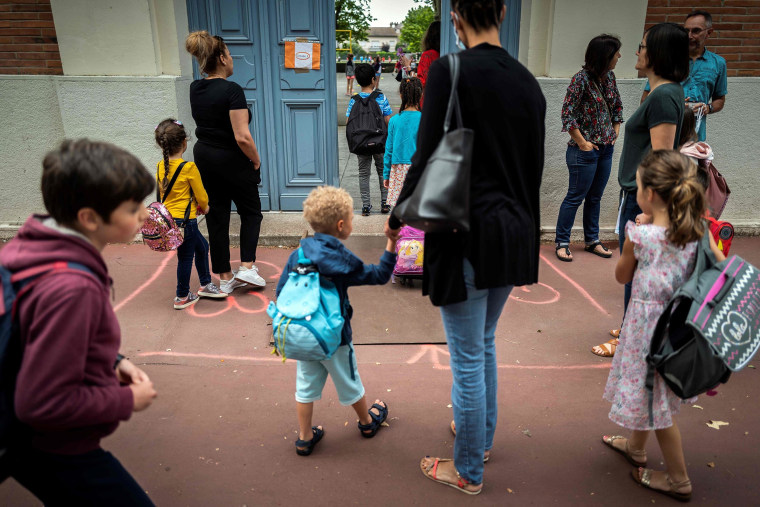 Image: Parents and children arrive at the Jules Julien elementary school in Toulouse, southern France, on June 22, 2020 following the reopening of schools