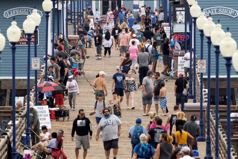 Image: People walk on the beach pier in Oceanside