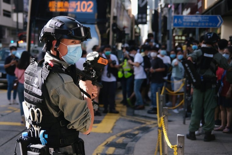 Image: A riot police officer holds a pepper spray projectile as he stands guard to stop a mass gathering during a protest in Hong Kong.