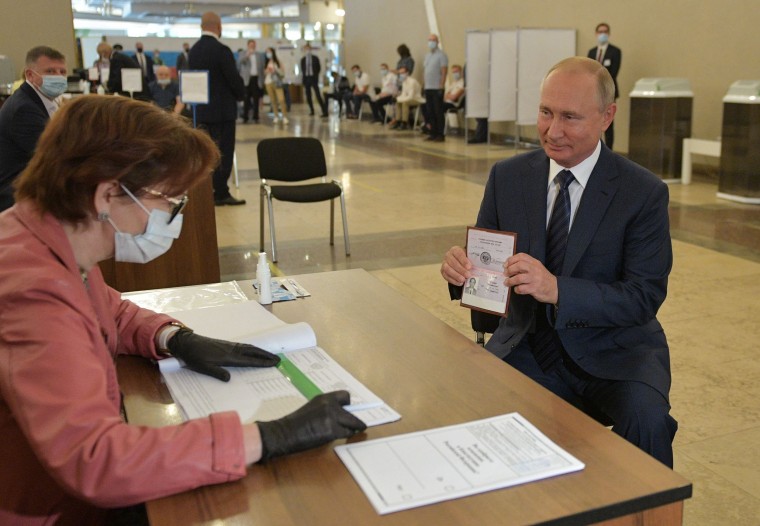 Image: Russian President Vladimir Putin shows his passport to a member of a local electoral commission as he arrives to cast his ballot in a nationwide vote on constitutional reforms at a polling station in Moscow