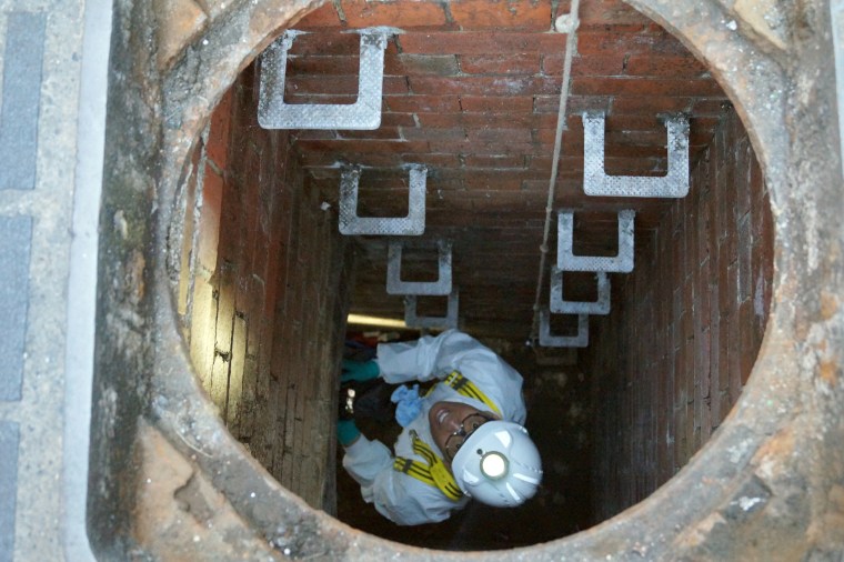 Image: A water company worker climbs down into a sewage pipe in London.