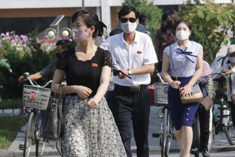 Image: People wearing masks walk in Pyongyang, North Korea on Friday.