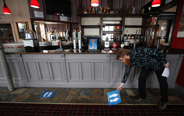 Image: Owner Are Kjetil Kolltveit from Norway places markers for social distancing on the front of the bar at the Chandos Arms pub in London